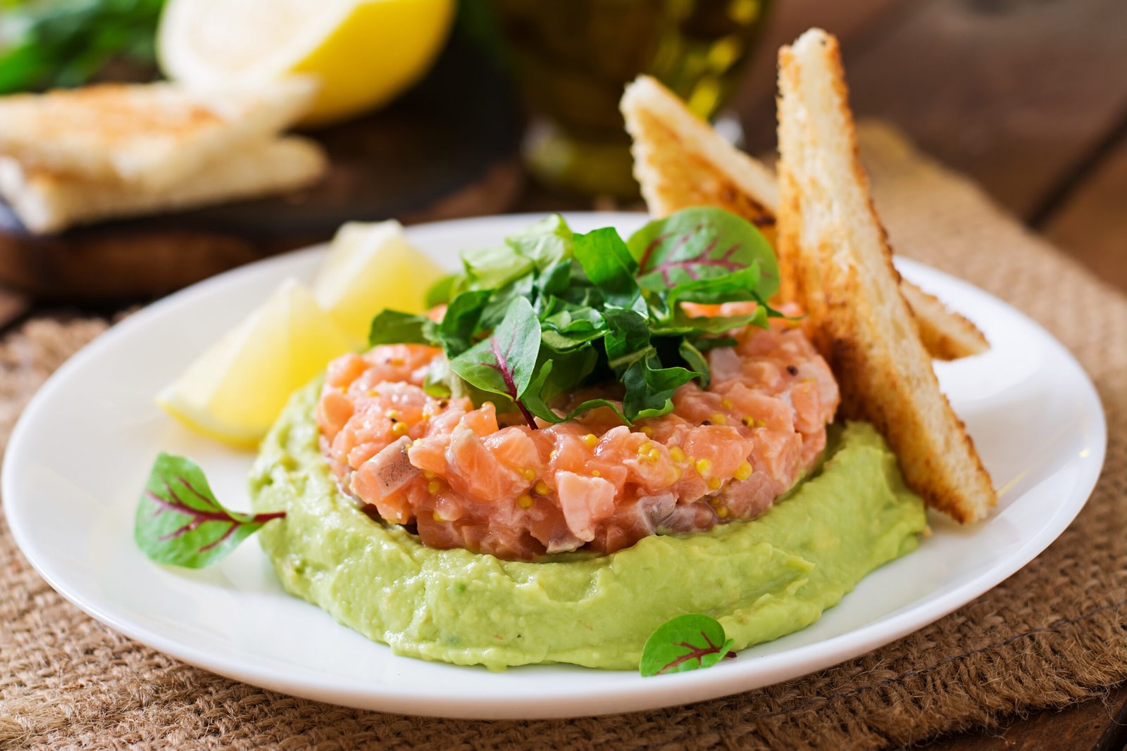 dans une assiette blanche, tartare de saumon sur une mousse à l'avocat